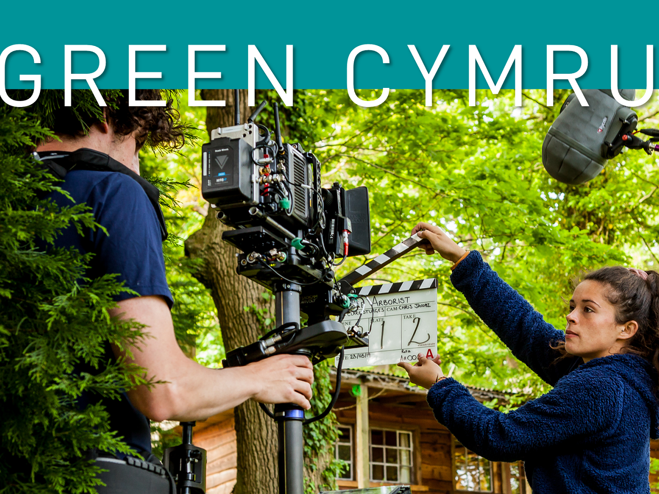 Image reads: Green Cyru and features man holding a camera and woman holding a clapper board