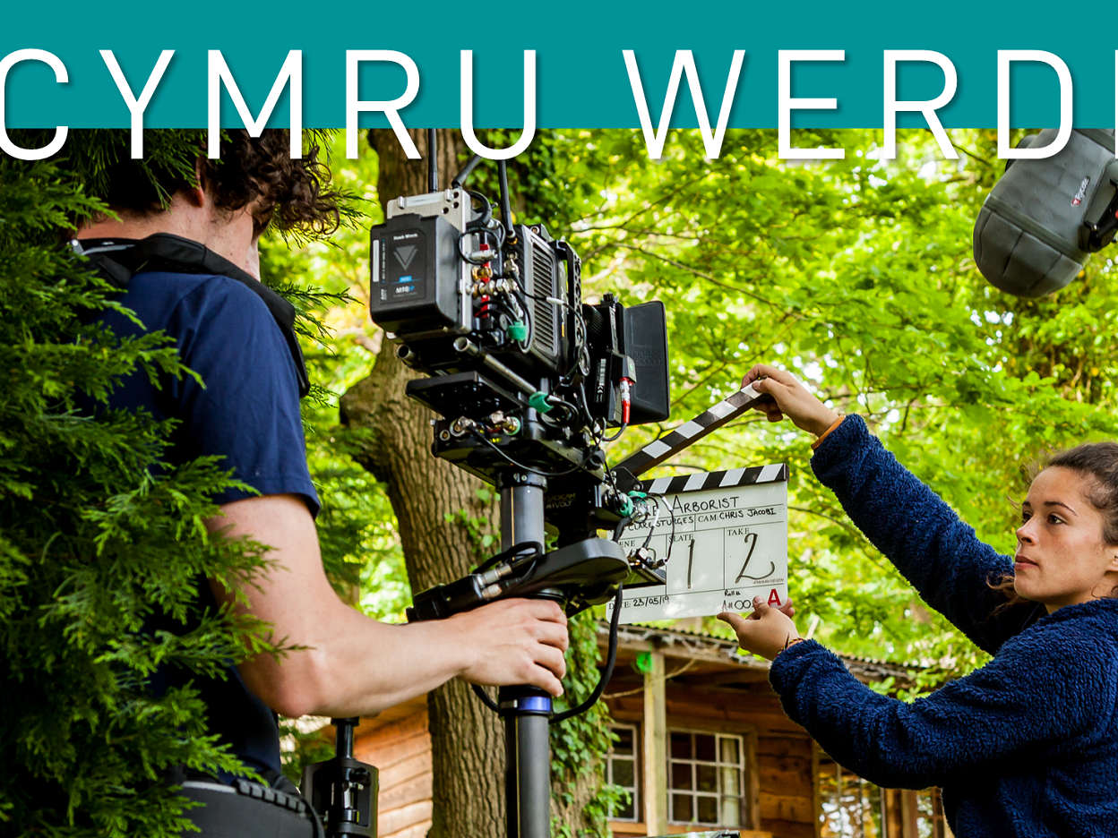 Image reads: Cymru Werdd and features man holding a camera and woman holding a clapper board